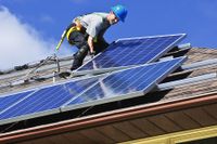 Ein Installateur einer Photovoltaikanlage / Solaranlage auf dem Dach eines Hauses